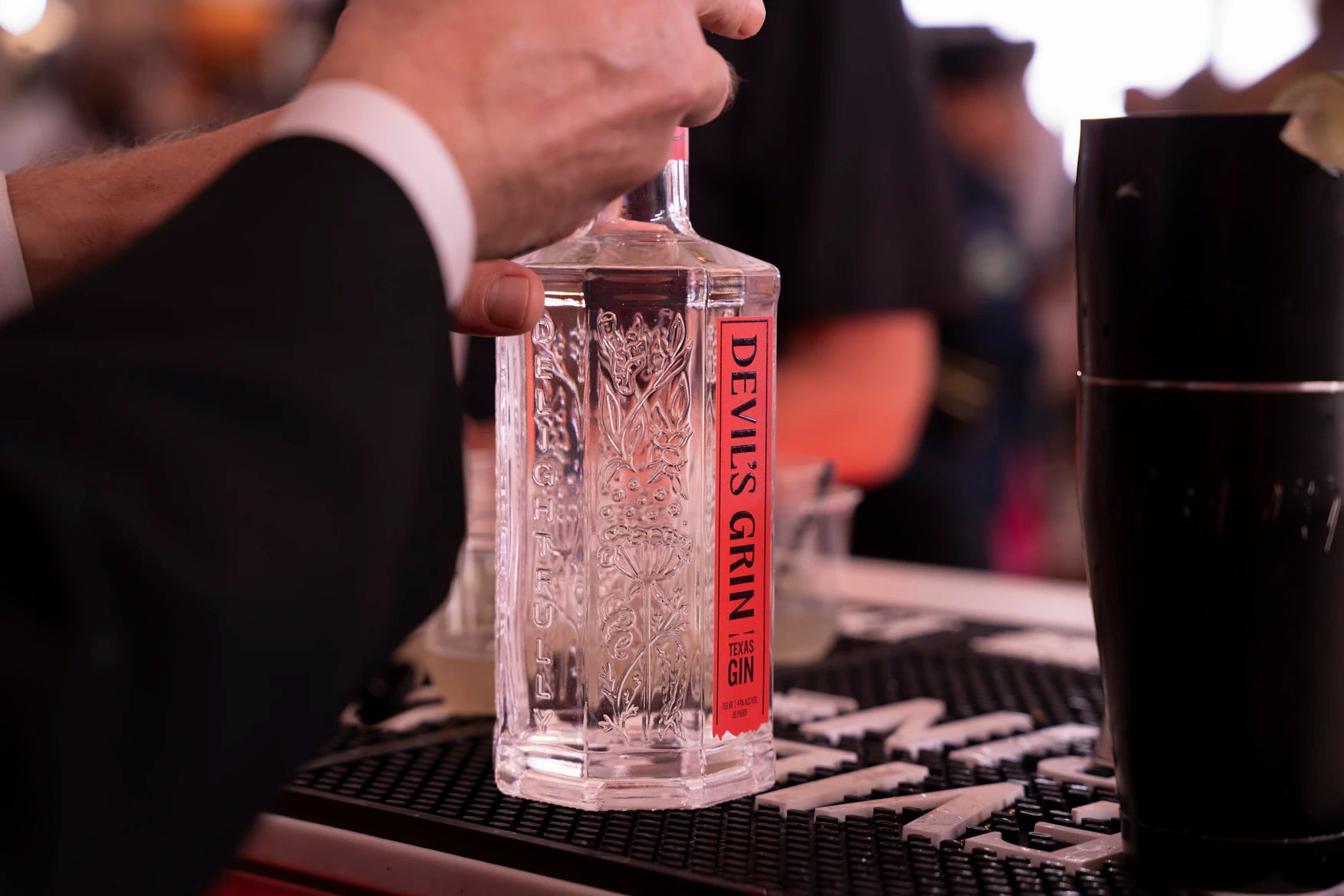 Bartender holding a bottle of Devil's Grin Texas Gin at a bar event