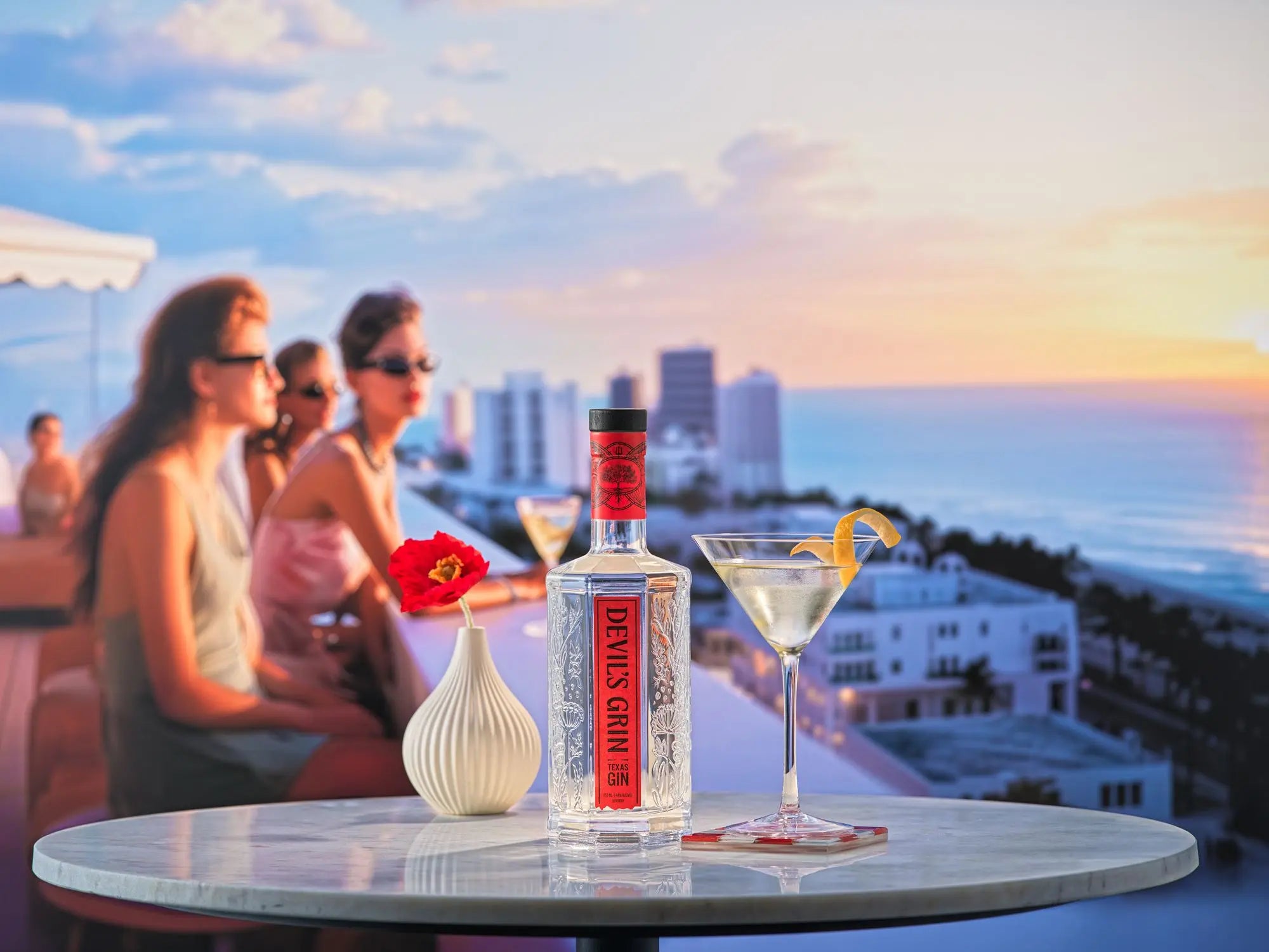 Devil&rsquo;s Grin bottle and a martini on a rooftop table at sunset